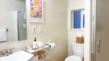 A bathroom with a sink, toilet, and a framed artwork above the mirror.