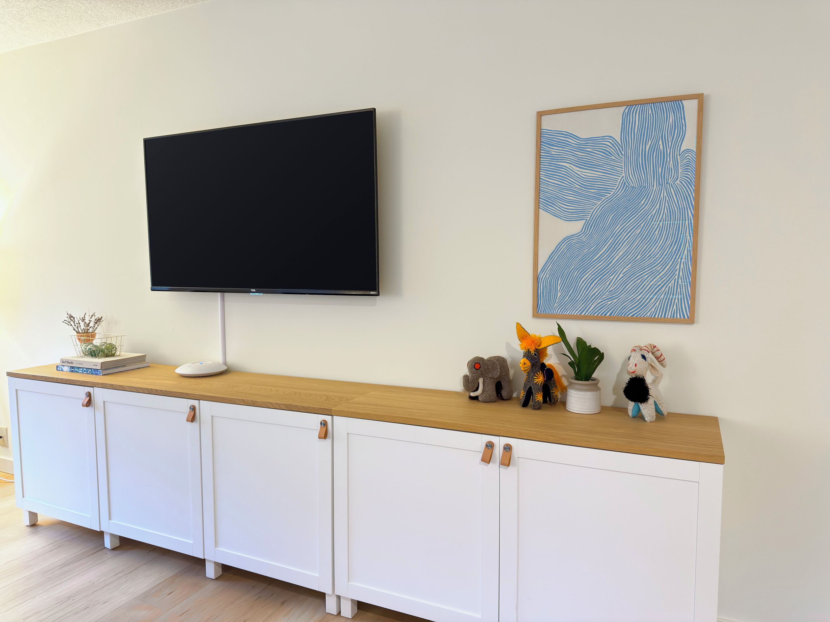 A flat-screen TV mounted on a wall above a wooden console with storage cabinets.