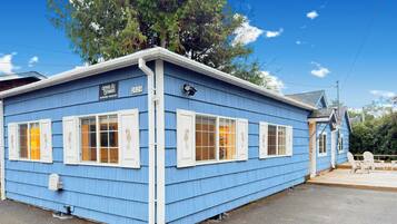 A blue building with white shutters, a sign with the year 2020, and a small deck area with chairs.