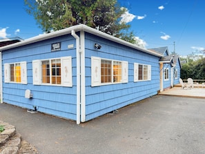 A blue building with white shutters, a sign with the year 2020, and a small deck area with chairs. - 2 Bedroom Surfer's Bungalow in Seaside (Seaside)