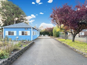 A blue building with a sign, a paved driveway, and outdoor seating. - 2 Bedroom Surfer's Bungalow in Seaside (Seaside)