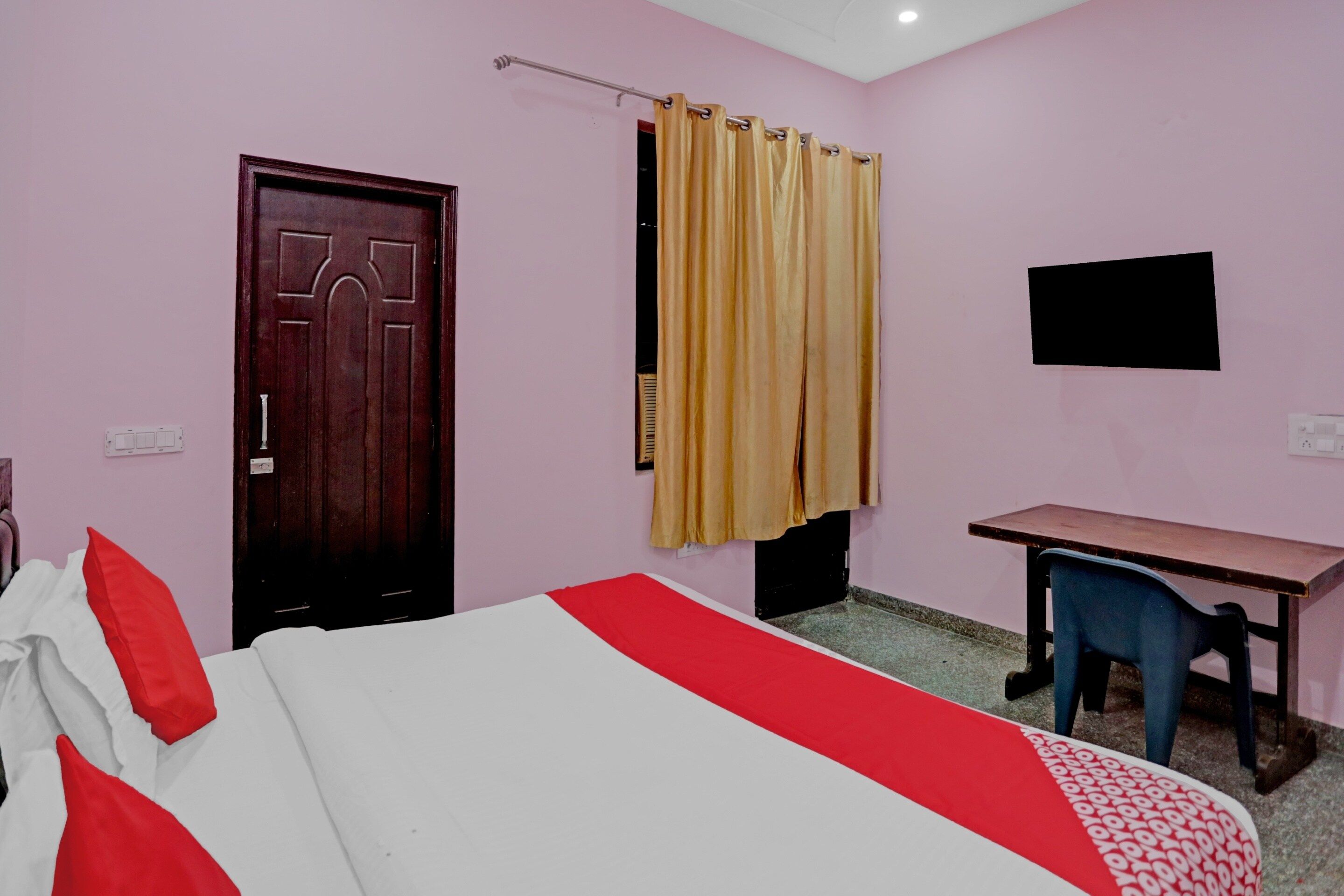 A room with a bed, a desk, a chair, a television, and a door.