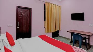 A room with a bed, a desk, a chair, a television, and a door.