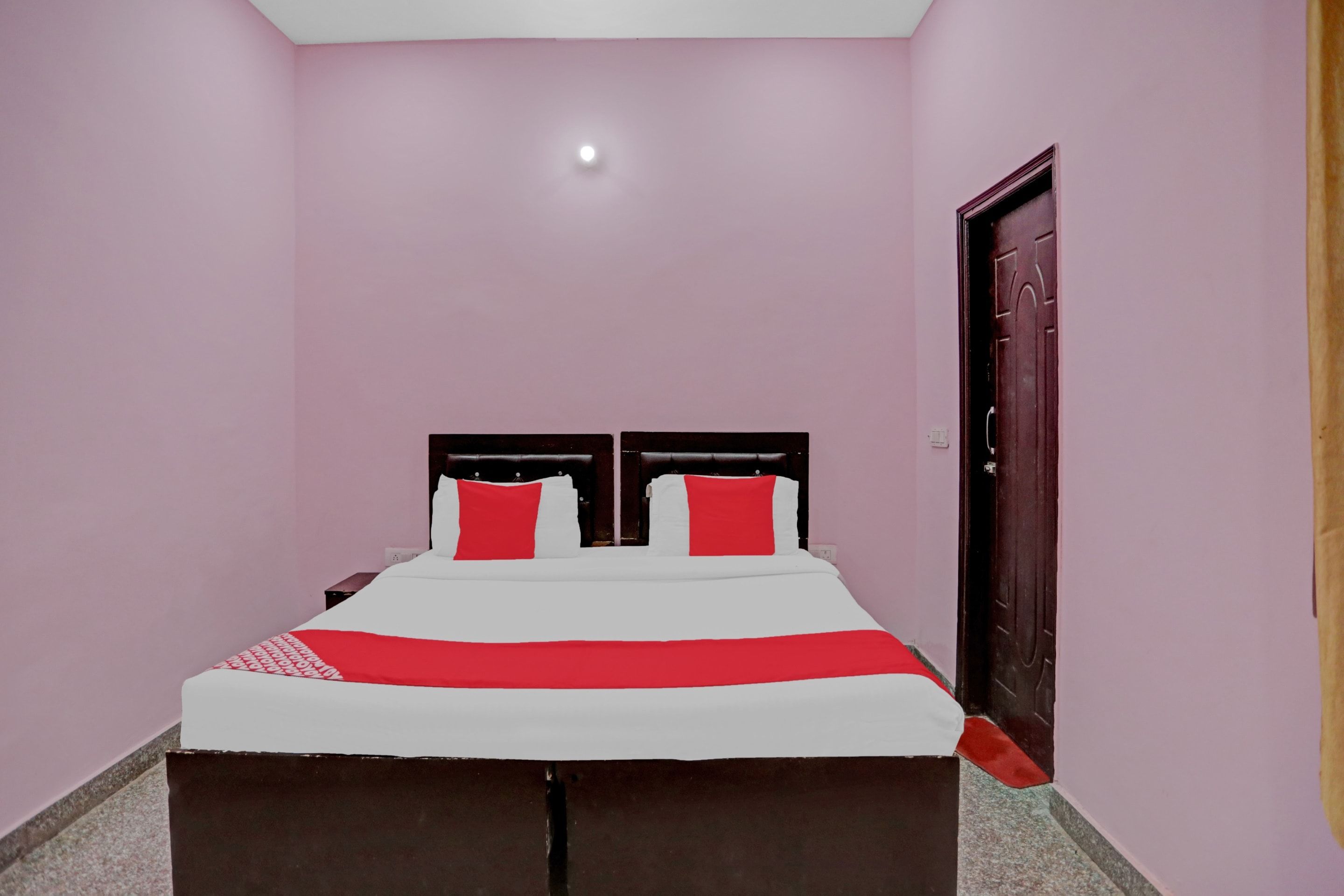 Un dormitorio con cama, dos almohadas, una mesita de noche y una puerta.