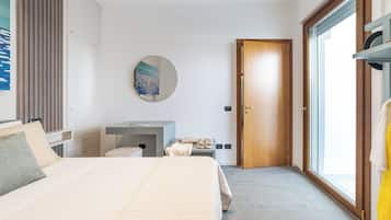 Una camera d'hotel moderna con un letto grande, un comodino, uno specchio, un armadio e vista all'esterno tramite una porta vetrata.