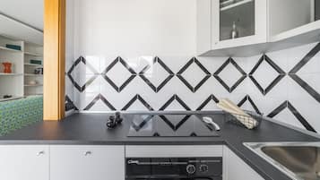 Una cucina con zoccolo a mosaico a motivi a spina di pesce bianco e nero, un piano di lavoro nero e una lavastoviglie.