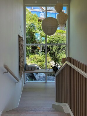 A staircase leading to a landing with a view of greenery outside. - Architect-designed villa with sea views near Tjörn (Stenungsund)
