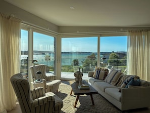 A spacious living room with a large glass door leading to a balcony with a view of the sea. - Architect-designed villa with sea views near Tjörn (Stenungsund)