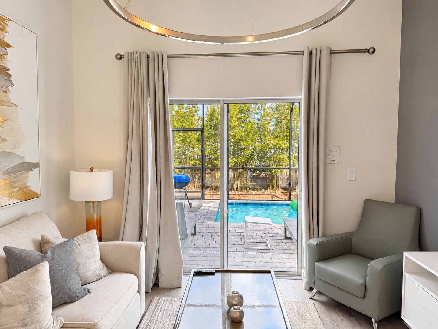 Ein modernes Wohnzimmer mit Sofa, Couchtisch und Blick auf Pool und Außenbereich.