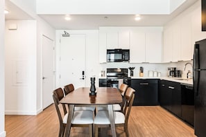 A modern kitchen with white cabinets, a black microwave, and a black refrigerator. - Artsy Space in Lil Tokyo-Free Parking-1Mi to DTLA (Los Angeles)