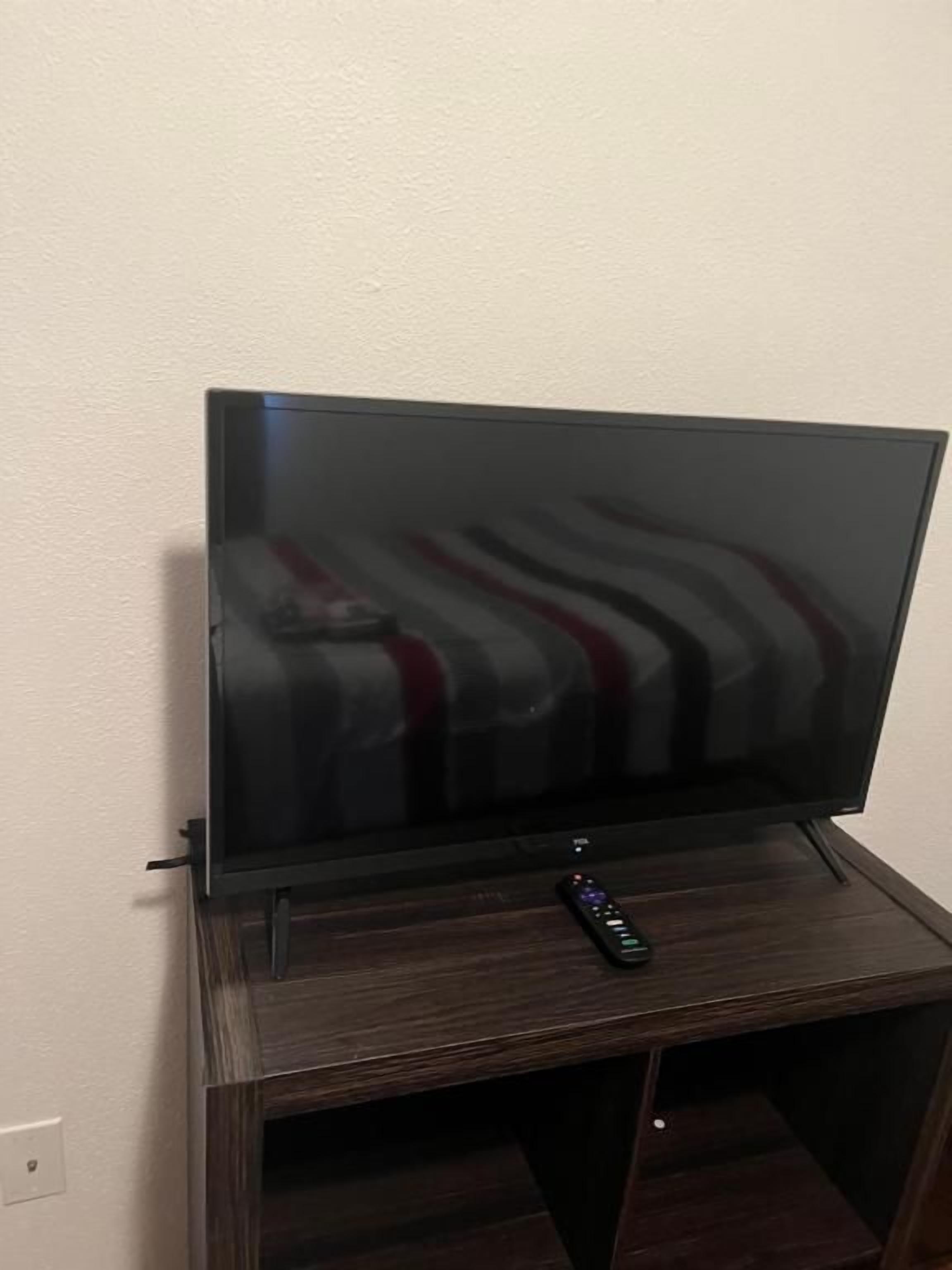 Un televisor de pantalla plana sobre un atril de madera con un control remoto encima.