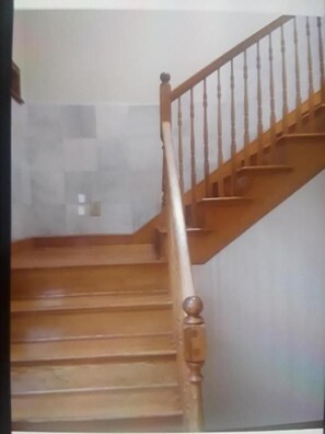 Una escalera de madera con barandilla que sube a un piso superior.