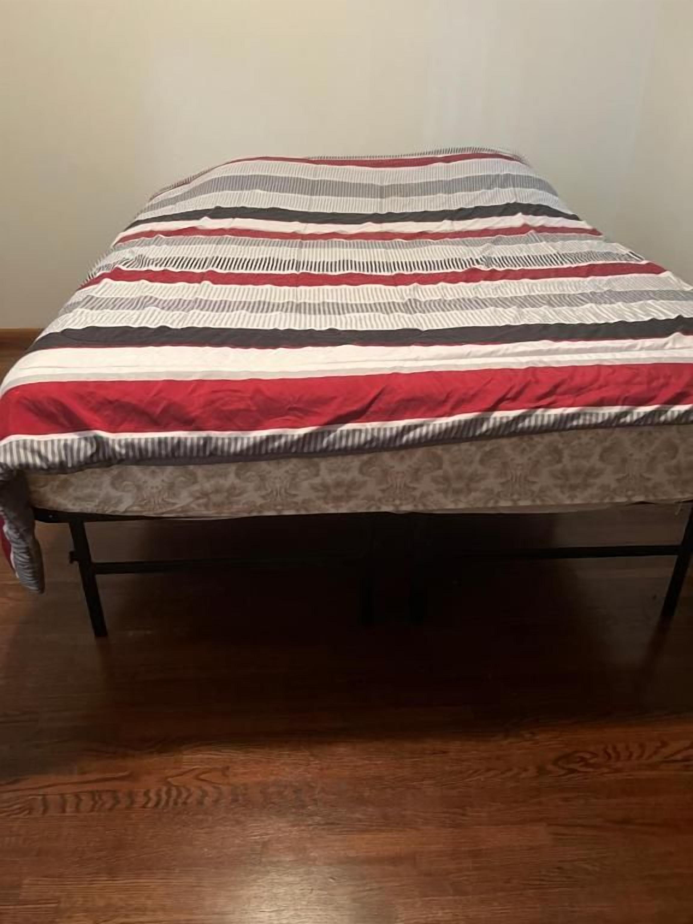 Una cama con una colcha a rayas y un cojín estampado.