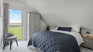 A bedroom with a bed, a chair, a nightstand, and a wardrobe. - Meadow View - outside Cheltenham with hot tub and games room, Sleeps 6 (Sandhurst)