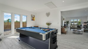 A pool table in a room with a sliding glass door leading to an outdoor area, a sofa, and a coffee table. - Meadow View - outside Cheltenham with hot tub and games room, Sleeps 6 (Sandhurst)