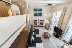 Un salon moderne comprenant un canapé, un téléviseur à écran plat et une bibliothèque.