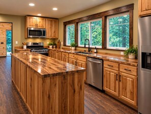 A modern kitchen with wooden cabinets, stainless steel appliances, and large windows.