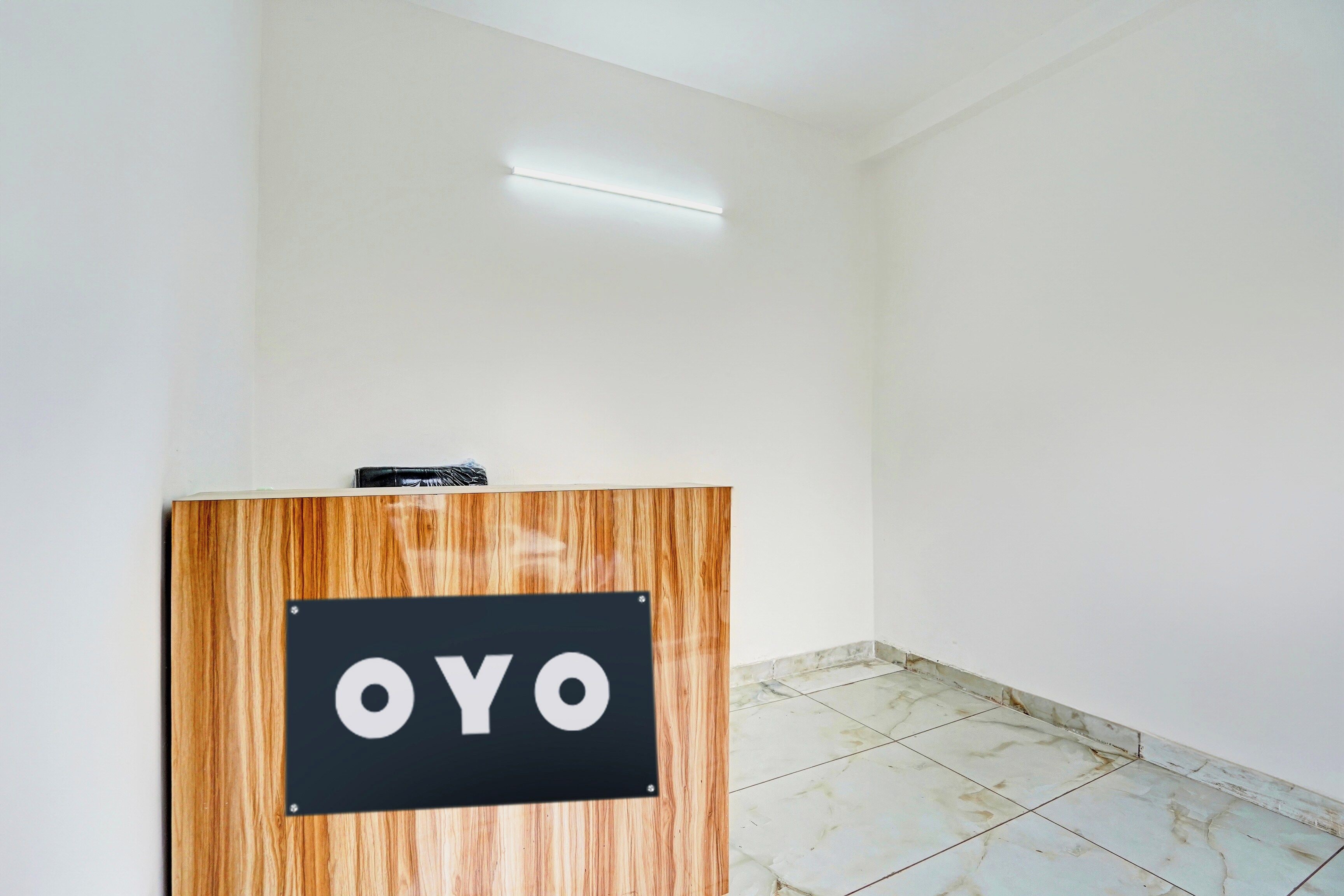A reception desk with a sign that reads 'OYO' in a room with white walls and a tiled floor.
