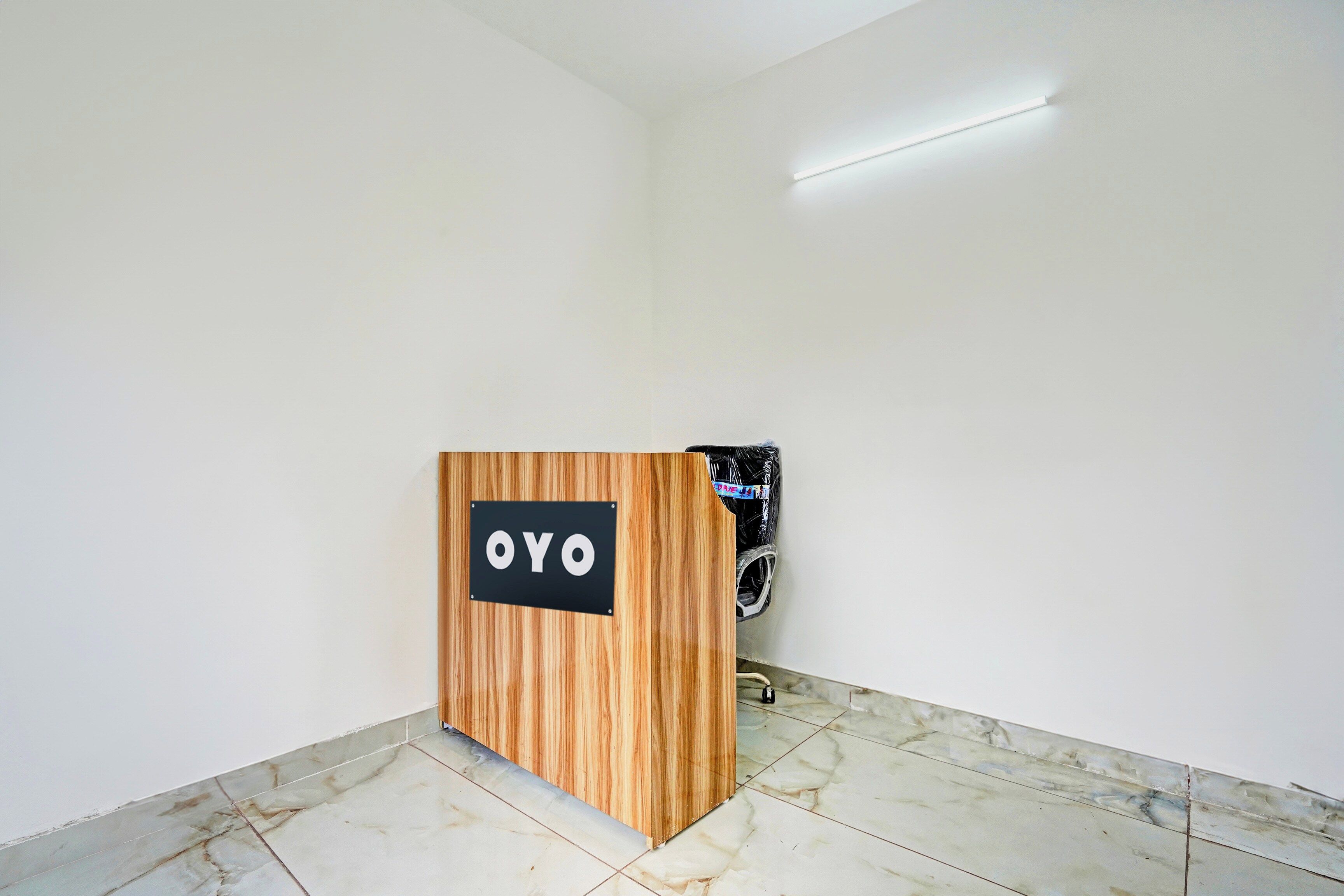 Un comptoir d'accueil avec une enseigne indiquant « OYO », situé dans une pièce aux murs blancs et au sol carrelé.