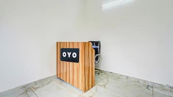 A reception desk with a sign that reads 'OYO' in a room with white walls and a tiled floor.