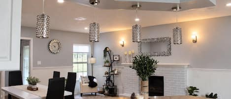 A modern kitchen with granite countertops, hanging crystal chandeliers, and a fireplace.