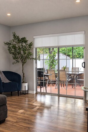 A room with a dark blue sofa, a potted plant, a sliding glass door leading to an outdoor patio with chairs and tables. - Spacious 5-bedroom house in wonderful Brandon with a wonderful Pool. (Brandon)