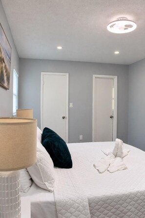 A hotel room with a bed, a bedside lamp, a painting on the wall, and two doors. - Spacious 5-bedroom house in wonderful Brandon with a wonderful Pool. (Brandon)