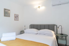 A neatly made bed with white linens and a brown throw blanket, two bedside tables with lamps, and two framed pictures on the wall. - New Listing (Lucca)
