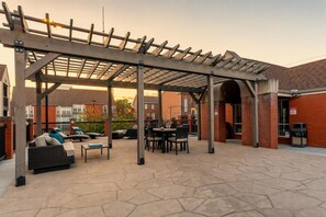 An outdoor patio with a pergola, seating, and a brick building in the background. - Walkable SoBro house near Broadway, sleeps 8, funky decor throughout (Nashville)