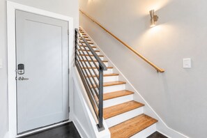 A staircase with a wooden handrail and a white door with a keypad lock. - Nashville-themed home with fire pit, sleeps 12, near 12 South & the Gulch (Nashville)