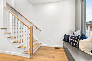 A modern interior with a wooden staircase, a bench with cushions, and a window with a view. - Nashville house with private rooftop patio near Broadway, sleeps 12 (Nashville)
