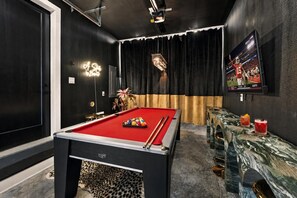 A pool table with balls, a bar area with glasses, and a television displaying a sports event. - Rooftop fire pit & game room, sleeps 10 near downtown Nashville & Broadway (Nashville)