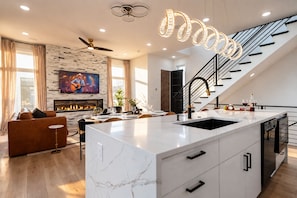 A modern kitchen with a marble island, a built-in stove, and a staircase leading to an upper level. - Rooftop fire pit & game room, sleeps 10 near downtown Nashville & Broadway (Nashville)
