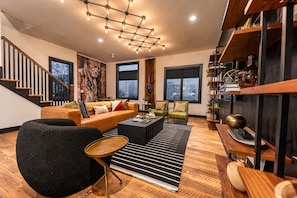A modern living room with a sofa, chairs, a coffee table, and a bookshelf. - Fall in Nashville: skyline-view house, 4 ensuite baths, sleeps 12 (Nashville)