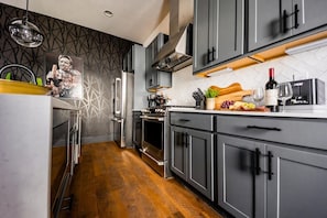 A modern kitchen with grey cabinets, stainless steel appliances, and a wooden floor. - Fall in Nashville: skyline-view house, 4 ensuite baths, sleeps 12 (Nashville)