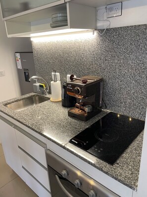 A kitchen with a built-in stove, a coffee maker, and a sink. - New Listing (Buenos Aires)
