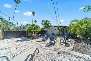 A backyard with outdoor seating, palm trees, and a building in the background. - Serene 2BR with Expansive Backyard Oasis (St. Petersburg)