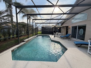 An indoor swimming pool with a glass ceiling, surrounded by lounge chairs and a patio area. - Greek Villa w/ Sunny Pool just 20 Min to Disney (Kissimmee)
