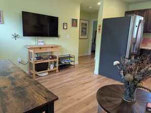 A living room with a flat-screen TV, wooden furniture, a shoe rack, and a decorative vase. - Private, comfy, colorful 2 bed 2 bath home close to everything (Sacramento)