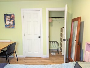 A room with a bed, a desk, a chair, a door, and a closet with hanging clothes. - Private, comfy, colorful 2 bed 2 bath home close to everything (Sacramento)