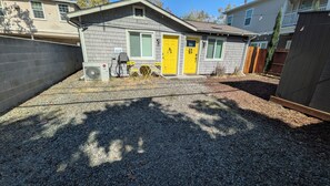 A residential property with a gravel driveway, a security camera, and a yellow door. - Private, comfy, colorful 2 bed 2 bath home close to everything (Sacramento)