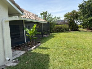 Il s’agit d’une propriété résidentielle dotée d’un patio couvert, d’une pelouse et de diverses plantes tropicales.