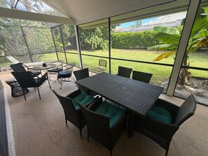 Une terrasse extérieure avec une table et des chaises, entourée de murs en verre.