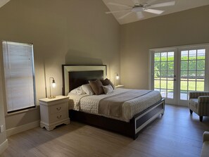 A bedroom with a bed, nightstands, a lamp, a ceiling fan, and a large window. - Lovely newly remodeled 3-bedroom, 3 bath house in charming Bonita Springs (Bonita Springs)