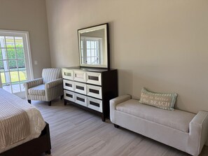 Une chambre à coucher comprenant un lit, une commode avec des tiroirs, une chaise, un canapé et une fenêtre donnant sur un paysage verdoyant.
