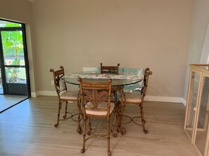 A dining area with a round glass table and four chairs with cushioned seats. - Lovely newly remodeled 3-bedroom, 3 bath house in charming Bonita Springs (Bonita Springs)