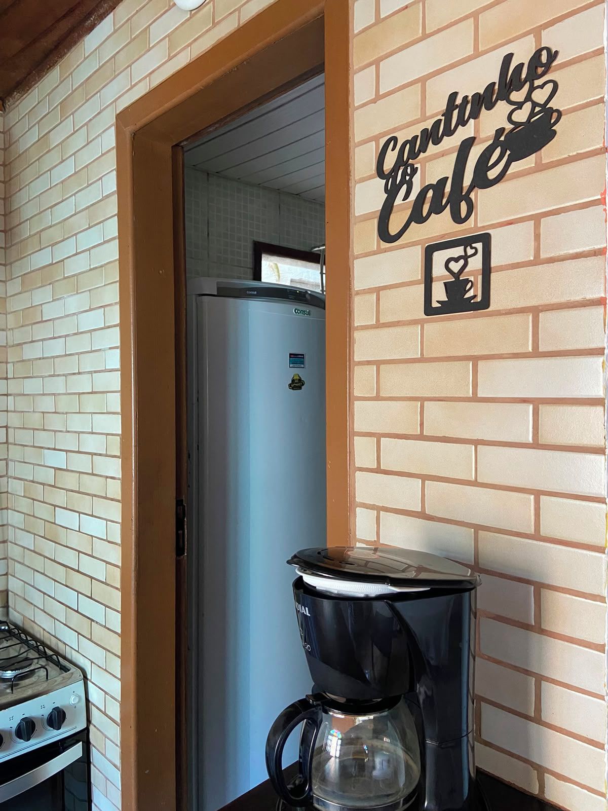 A kitchen area with a stove, a coffee maker, and a refrigerator.