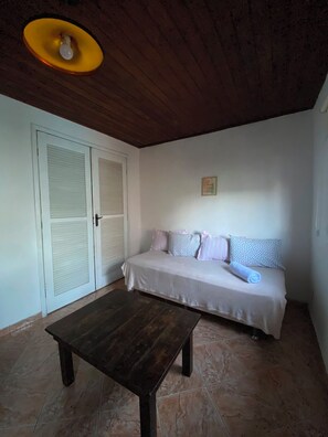 A room with a bed, a table, and a door. - New Listing (Arraial do Cabo)
