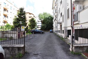A narrow street flanked by residential buildings with balconies, a gated entrance, and a parked car. - Jireh vacation home - Two Bedroom Apartment, Sleeps 5 (Rome)