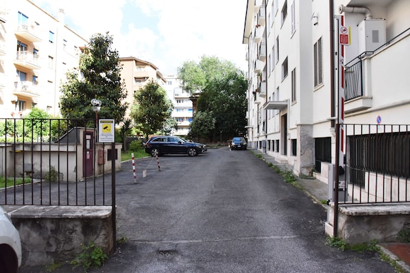A narrow street flanked by residential buildings with balconies, a gated entrance, and a parked car. - Jireh vacation home - Two Bedroom Apartment, Sleeps 5 (Rome)